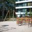 Kleine Fitnessanlage aus Holz auf sandigem Spielplatz mit Kletter- und Balanciermöglichkeiten.