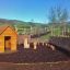 Holzspielhaus Natur Spielhaus für Kinder im Garten mit Zaun und Bäumen.