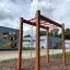 Horizontale Leiter II auf einem Spielplatz mit roten Sprossen und hölzernen Pfosten.