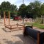 Kinder spielen auf einem Spielplatz mit Balancierspielnetz und weiteren Spielgeräten.