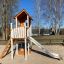 Lisas Spielturm mit Rutsche steht auf einem Spielplatz in einem sonnigen Park.
